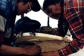 Kamashkushkatinau-nipi. Mani-Aten Penashue instructs her son, Maurice, in lacing snowshoes. Photo courtesy Camille Fouillard.